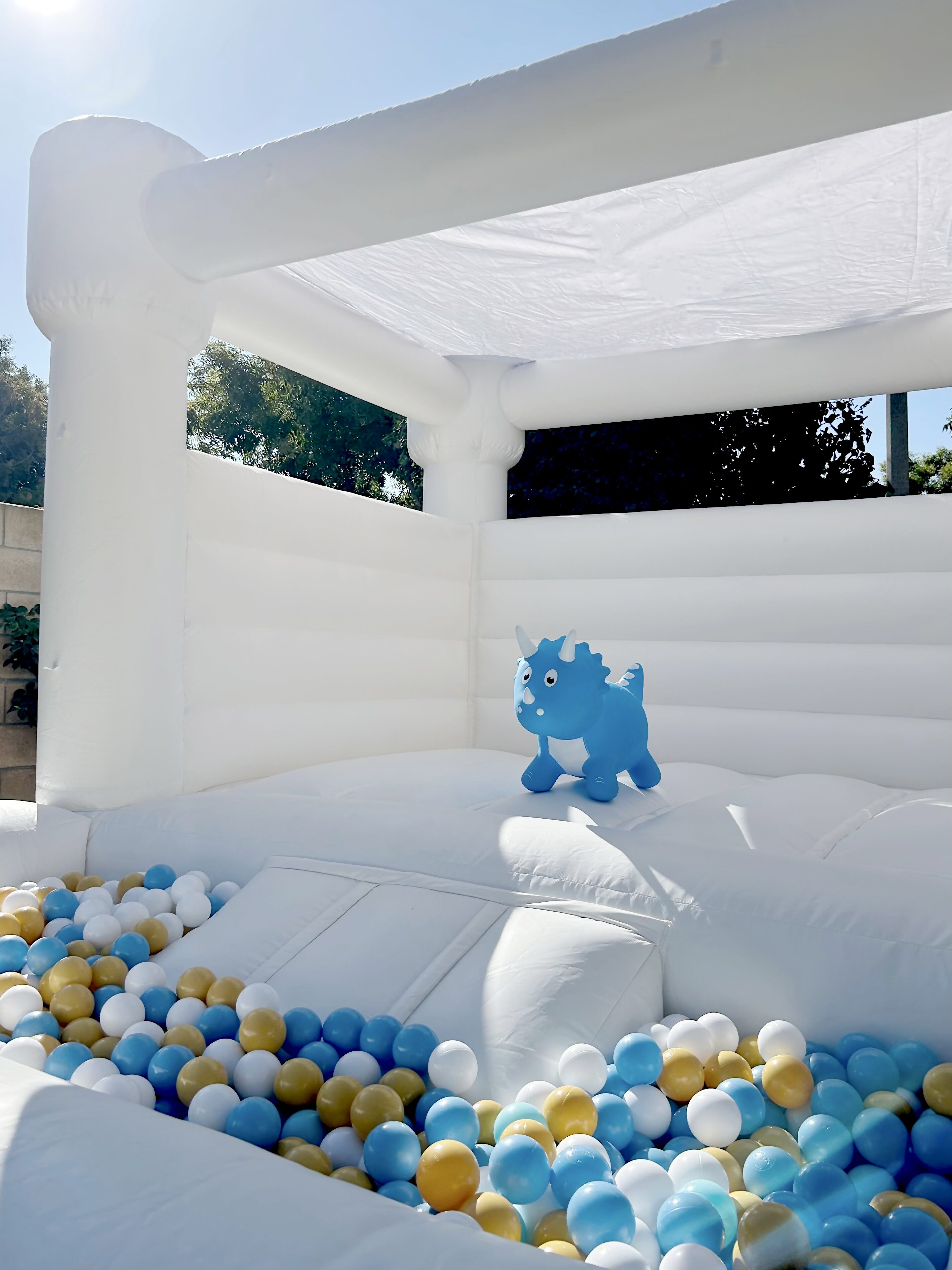 White bounce house with blue, white and gold ball pit