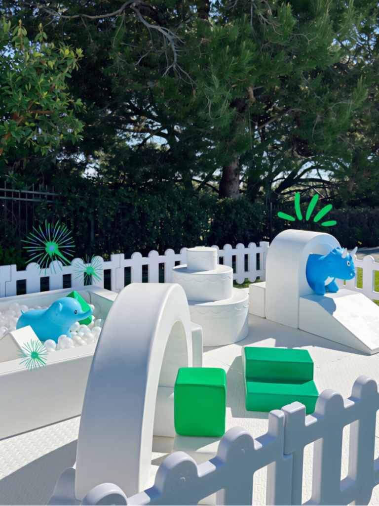 White soft play with blue and green hoppers outdoors