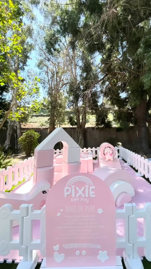 Pink soft play with PIXIE welcome sign in a backyard