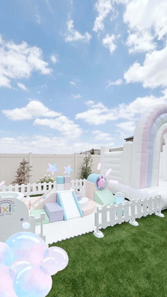Pastel soft play with white rainbow bounce house outdoors